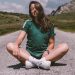 A girl sits on a road in the middle of nowhere, smiling while enjoying the warmth of the sun